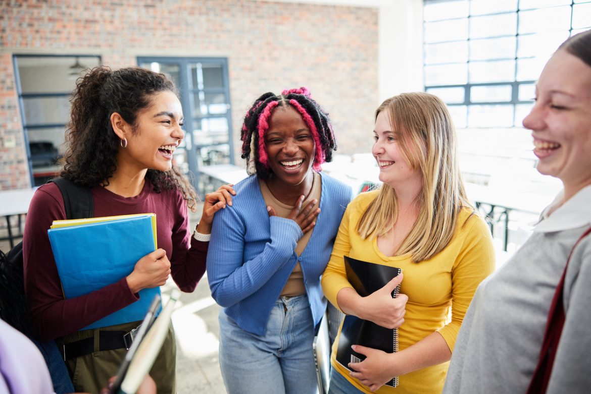 Group of diverse female college students laughing in a class at school